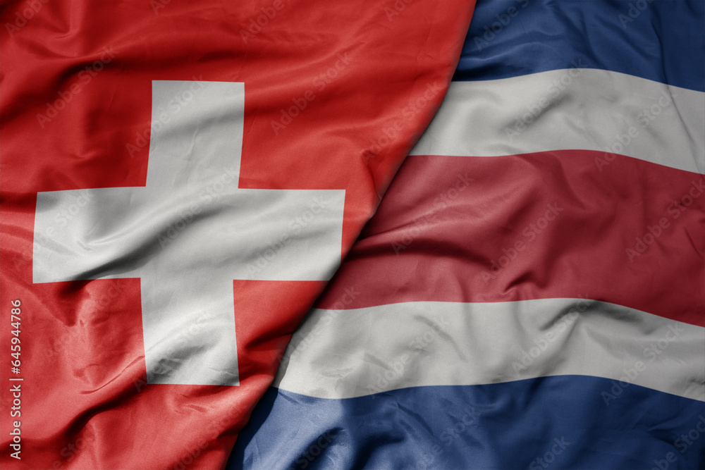 big waving national colorful flag of switzerland and national flag of costa rica .