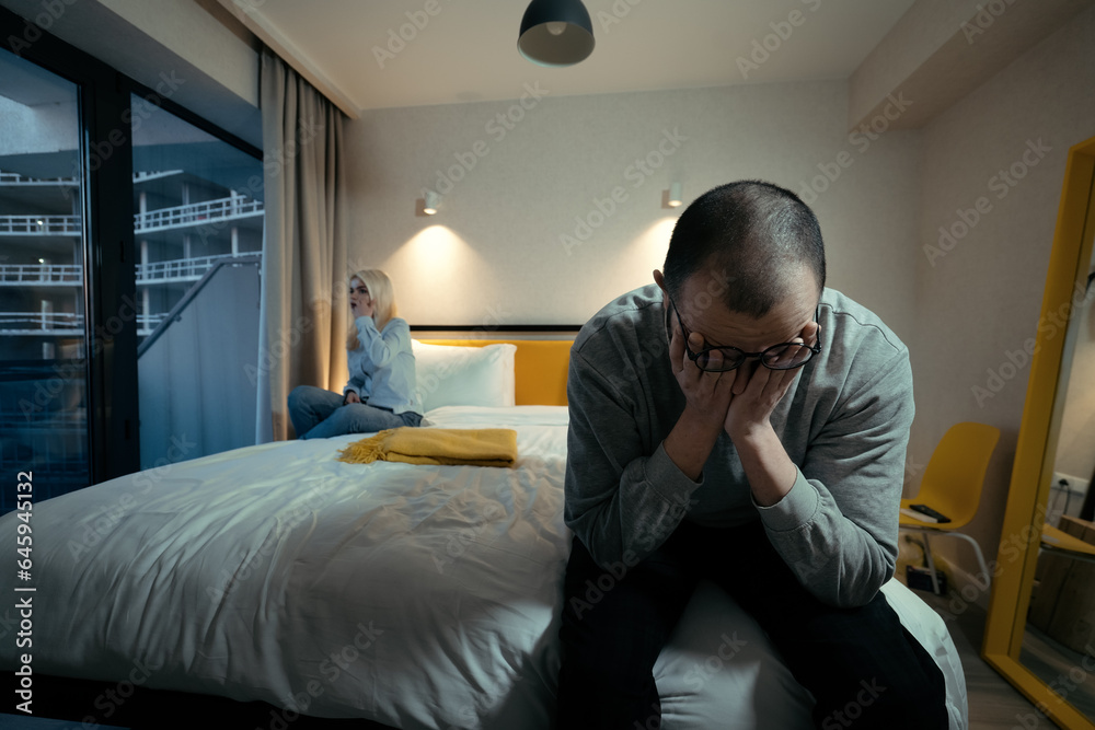Upset man sitting on edge of bed. Problems in relationships and intimacy. Treason concept.