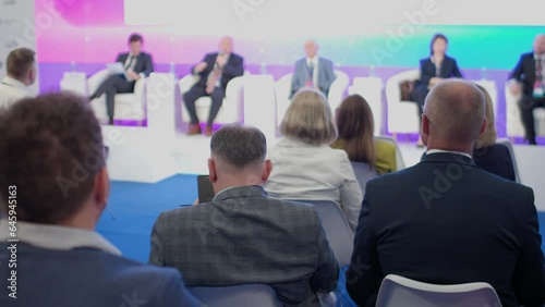The audience listens to speakers at a business conference. Back view. Slow motion. The concept of education and public speaking.