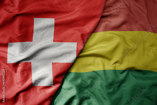 big waving national colorful flag of switzerland and national flag of bolivia .