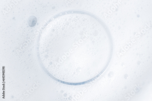 Washing agent foam in a Petri dish. On a blue background.