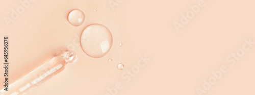 The gel dripping from the dropper is transparent in the form of round droplets on a beige background.