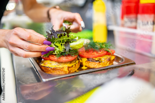 woman chef hand cooking burger with vegetables and meat on restaurant kitchen