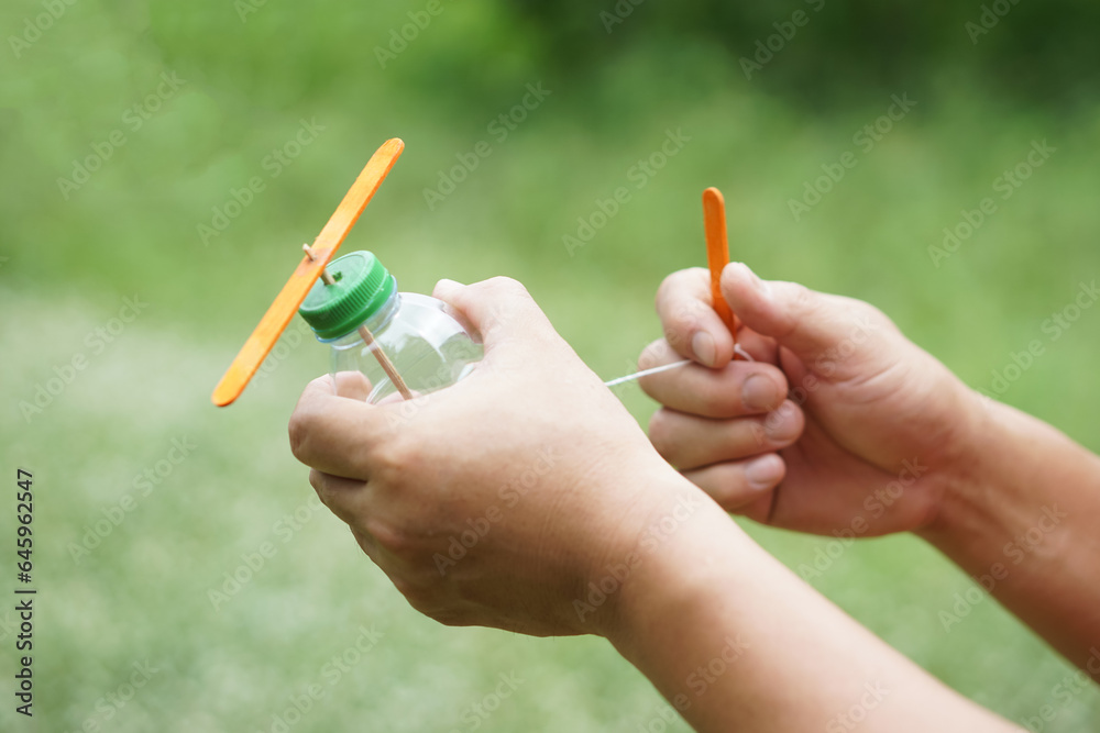 Close up hands hold DIY toy made from plastic bottle, rope and ice ...