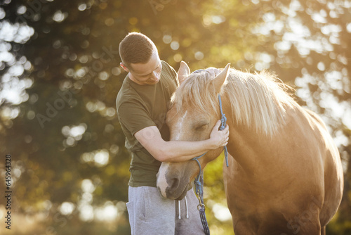 Man is embracing of theraphy horse. Themes hippotherapy, care and friendship between people and animals..