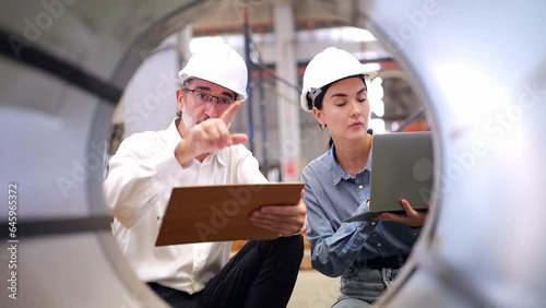 Wallpaper Mural Senior engineer holding a worksheet wearing safety helmet training and explaining to a beautiful female engineer wearing a hard hat, holding a laptop in the factory Industrial steel cutting machine.  Torontodigital.ca