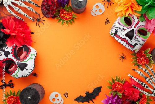 Dance with the Spirits on Dia de los Muertos. Top view photo of decorated skull masks with flowers, candles, skeleton hands, creepy decor on orange background with ad zone