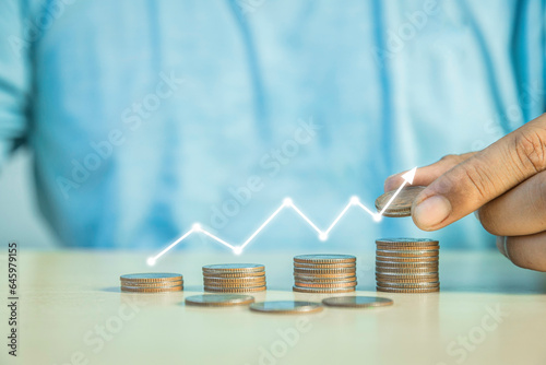 Man putting a coin on a pile of coins. Placing coins in a row from low to high is comparable to saving money to grow more, money-saving concept