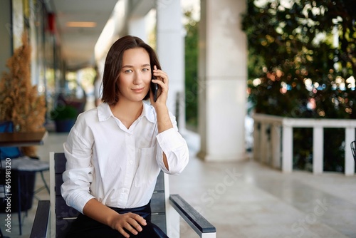 Portrait of a business woman using a phone near the office, concept of a strong and independent woman. Young happy business woman, confident positive female