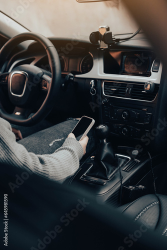 A girl using her phone, while sitting in her car. photo