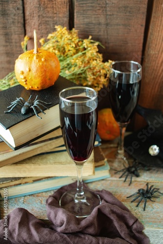 Celebrate Halloween, two glasses of red wine, vintage books, pumpkins and Halloween decorations on a wooden background