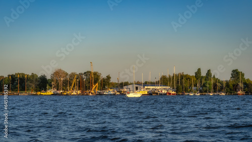 Shipyard and harbour of Szczecin Dabie marina with moored yachts and boats at sunset. Cranes and hangars in background, Poland