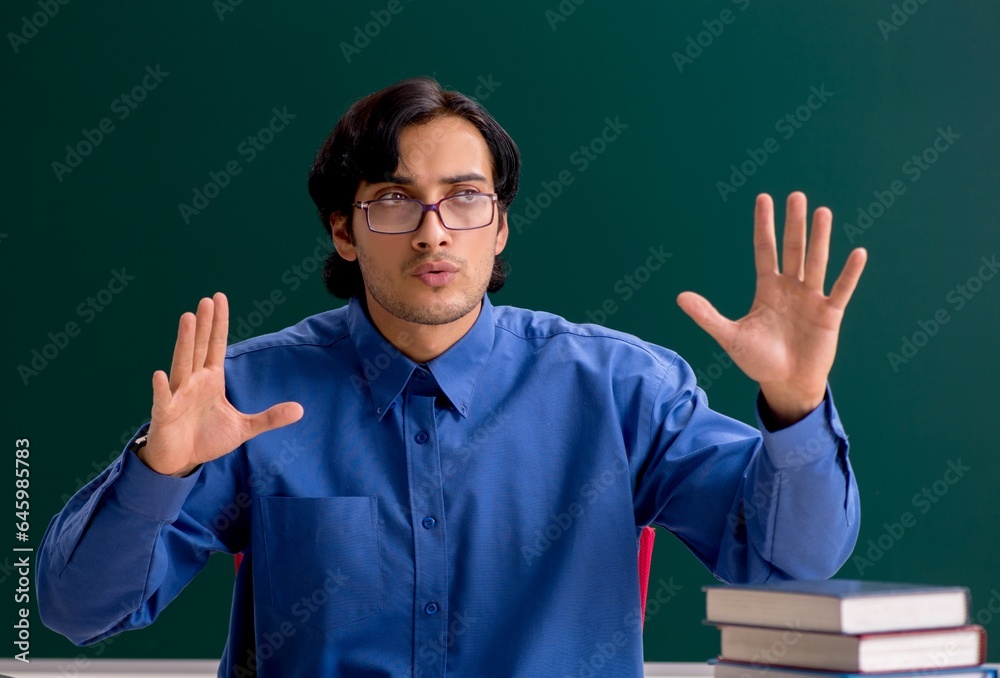 Young male teacher in front of chalkboard