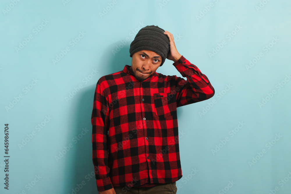 Confused young Asian man pursing his lips as if forbidden to say anything isolated on blue backdrop Confused young Asian man pursing his lips as if forbidden to say anything isolated on blue backdrop