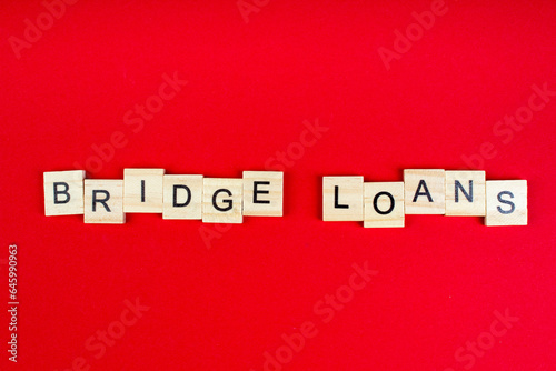Bridge loans- word composed fromwooden blocks letters on red background, copy space for ad text. photo