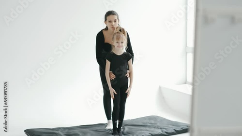 Professional cherleading trainer dancing with little girl, moving synchronically at dance class photo