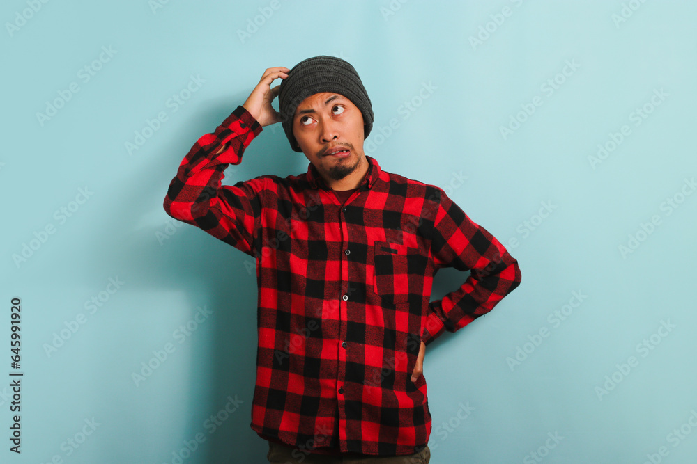 Pensive Young Asian man is scratching his head, trying to find solution, isolated on blue background Pensive Young Asian man is scratching his head, trying to find solution, isolated on blue background