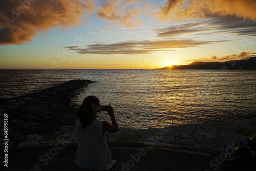 Obraz na płótnie Woman seating in Sunset Image of Agarie Beach in Nago, Okinawa, Japan - 日本 沖縄 名護 東江ビーチに座る女性 w salonie