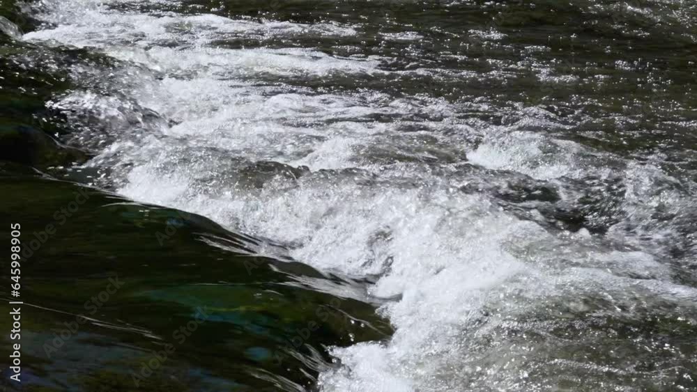 Slow motion of the splashing flowing water of a mountain river close up Slow motion of the splashing flowing water of a mountain river close up