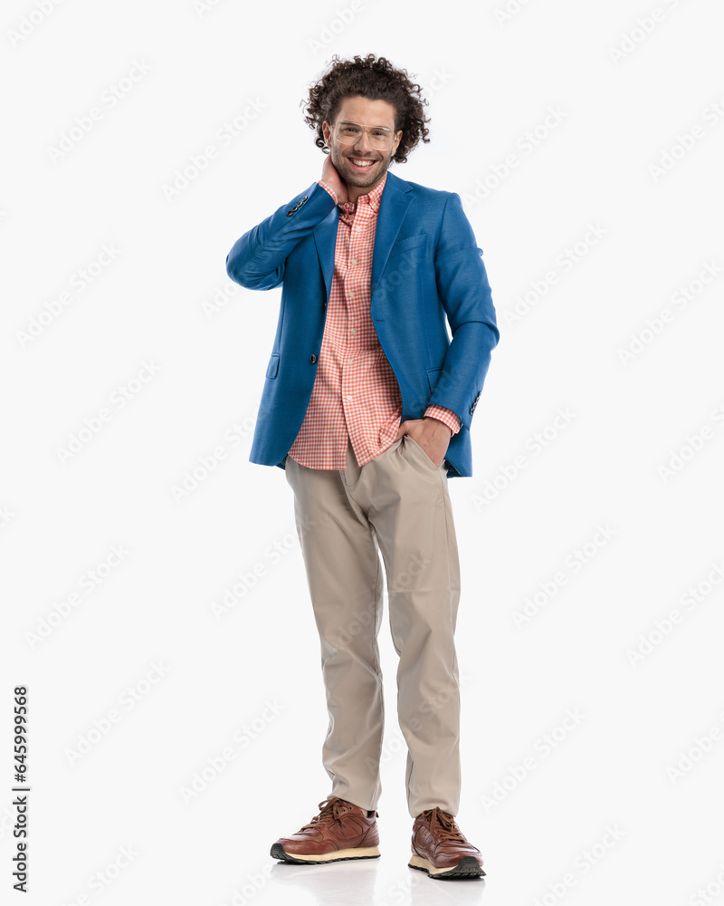 happy casual young man with curly hair with hand in pocket touching neck happy casual young man with curly hair with hand in pocket touching neck