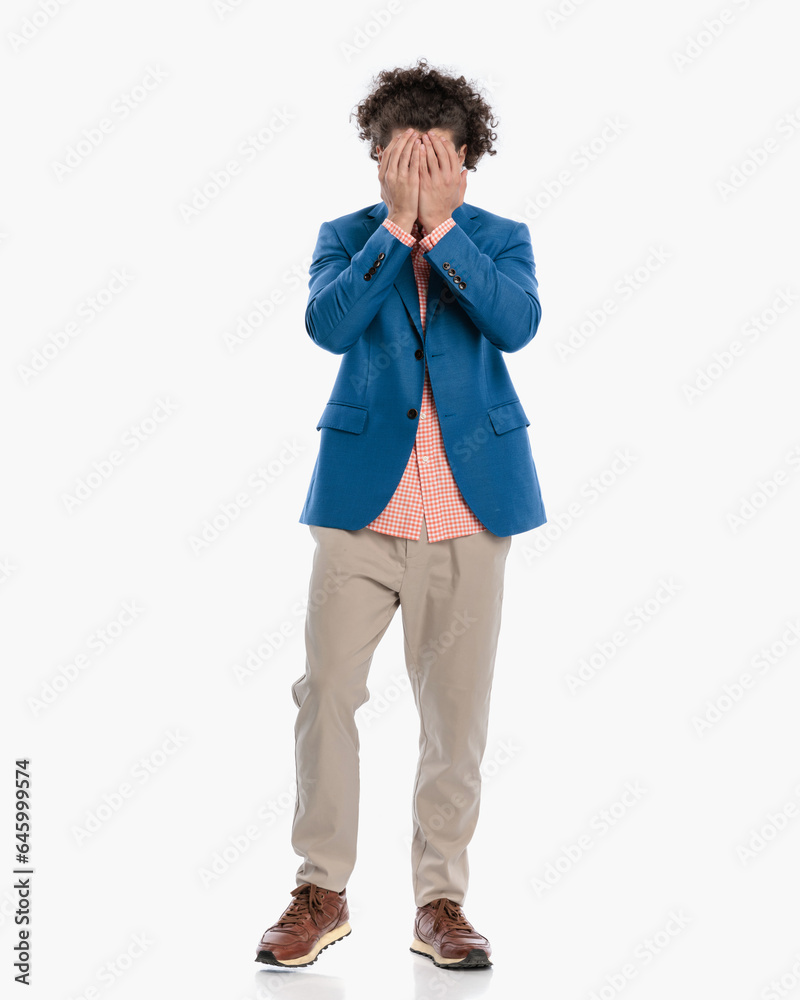 shy young man with curly hair covering face and hiding behind shy young man with curly hair covering face and hiding behind