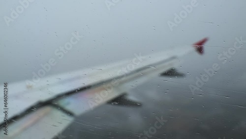 View from the porthole of an airplane of the wing and the rain flowing on the glass, during landing. Flight in bad weather conditions. Real time video.