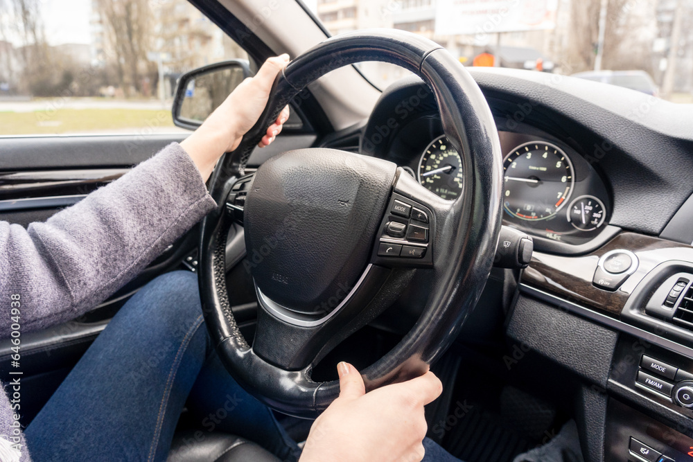 Women's hands holding steering wheel of the car. Driving