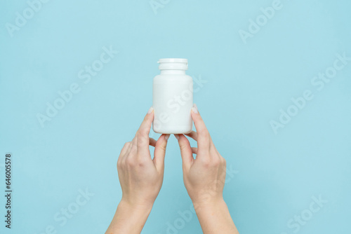 Woman's hand holds white plastic tube. Bottle for pill, capsule or supplement. Product branding mockup