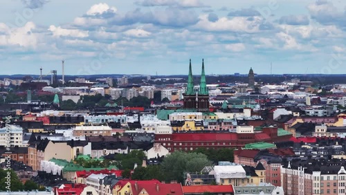 Aerial slide and pan footage of Johanneksenkirkko church towers above urban neighbourhood. Parallax effect. Helsinki, Finland photo