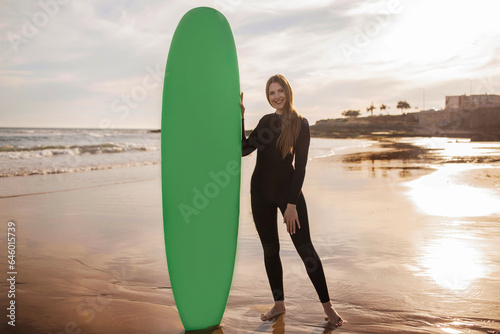 Professional Surfer Lady Standing On The Beach And Holding Surf Board