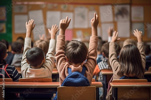 multicultural elementary school students raising their hands in a classroom © BOONJUNG