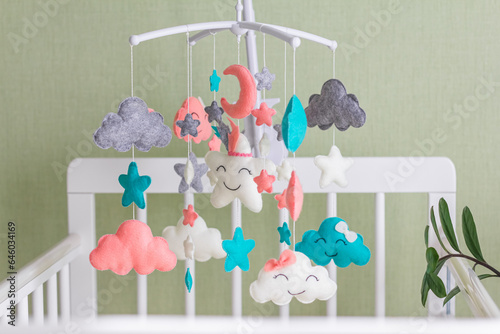 Cute mobile with clouds, stars and moon hanging on a crib in a children's room