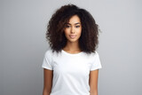 Young beautiful afroamerican woman model with dark curly hair in white t-shirt posing on light grey background