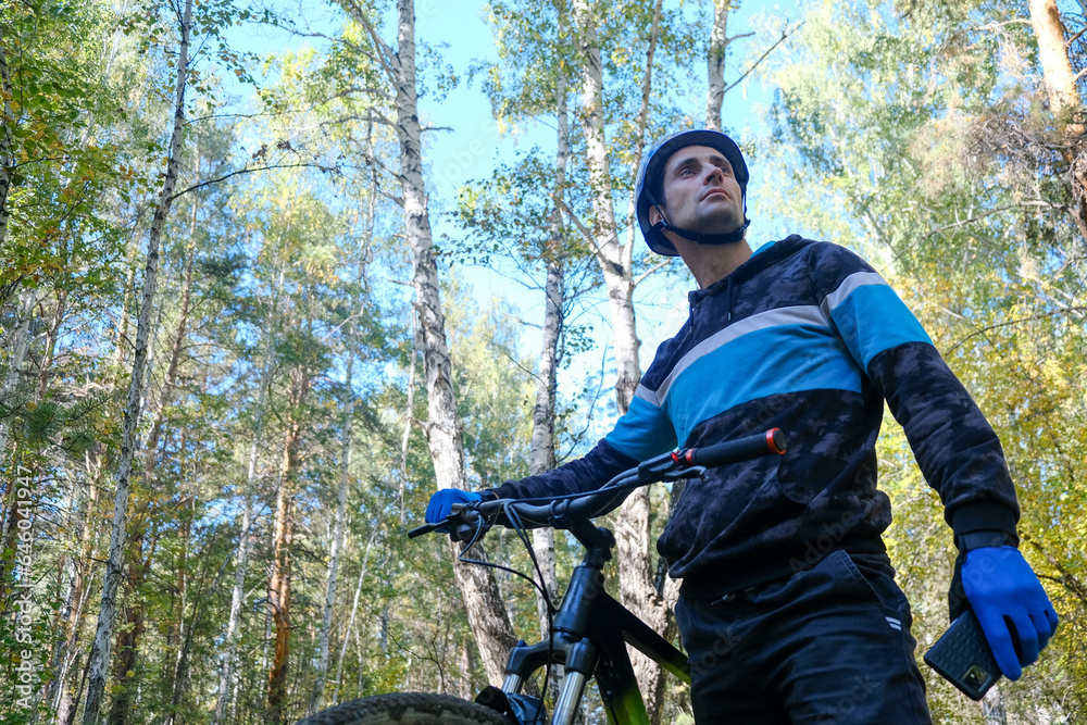 A cyclist in gear has stopped and is looking around in the woods.Active lifestyle A cyclist in gear has stopped and is looking around in the woods.Active lifestyle