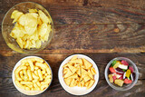 birthday or christmas, new year's party concept, a bowls of different chips and candies on wooden table