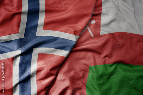 big waving national colorful flag of norway and national flag of oman .