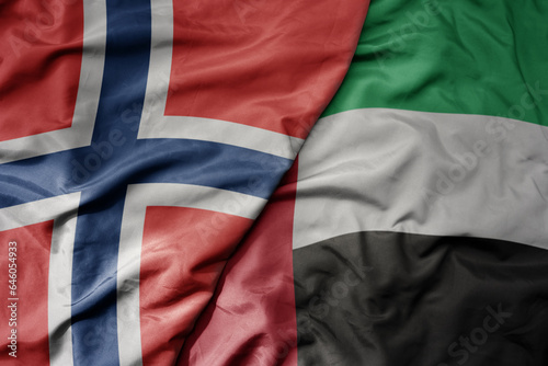 big waving national colorful flag of norway and national flag of united arab emirates .