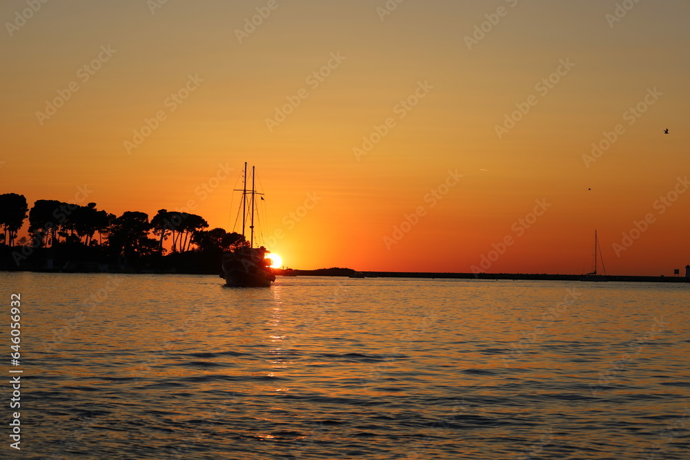 Sunset with boat silhouettes on the Adriatic sea in Porec, Istria, Croatia, Europe. Beautiful sunset by the Adria sea, The sun is setting over the sea, Porec