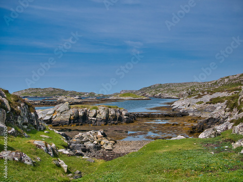 A rocky bay on the coast the island of Bernera (Great Bernera) in Loch Roag on the north-west coast of Lewis in the Outer Hebrides, Scotland, UK. Taken on sunny day with a blue sky in summer.