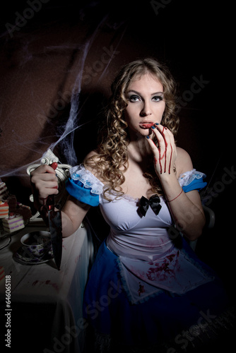 Halloween. Portrait of a young woman with a large kitchen knife. Dressed as Alice photo