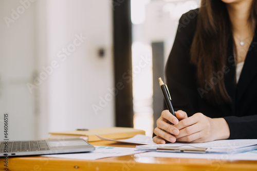 Asian Businesswoman Using laptop computer and working at office with calculator document on desk, doing planning analyzing the financial report, business plan investment, finance analysis concept.