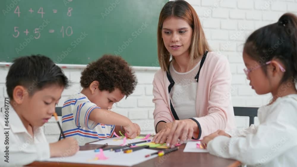 Students of different nationalities learning together in a classroom. Young female caucasian teacher working with little children group in class explaining. Back to kindergarten school. Students of different nationalities learning together in a classroom. Young female caucasian teacher working with little children group in class explaining. Back to kindergarten school.
