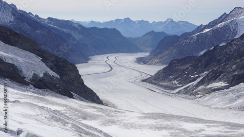 A valley containing a flowing river like ice glacier surrounded by snow covered mountains