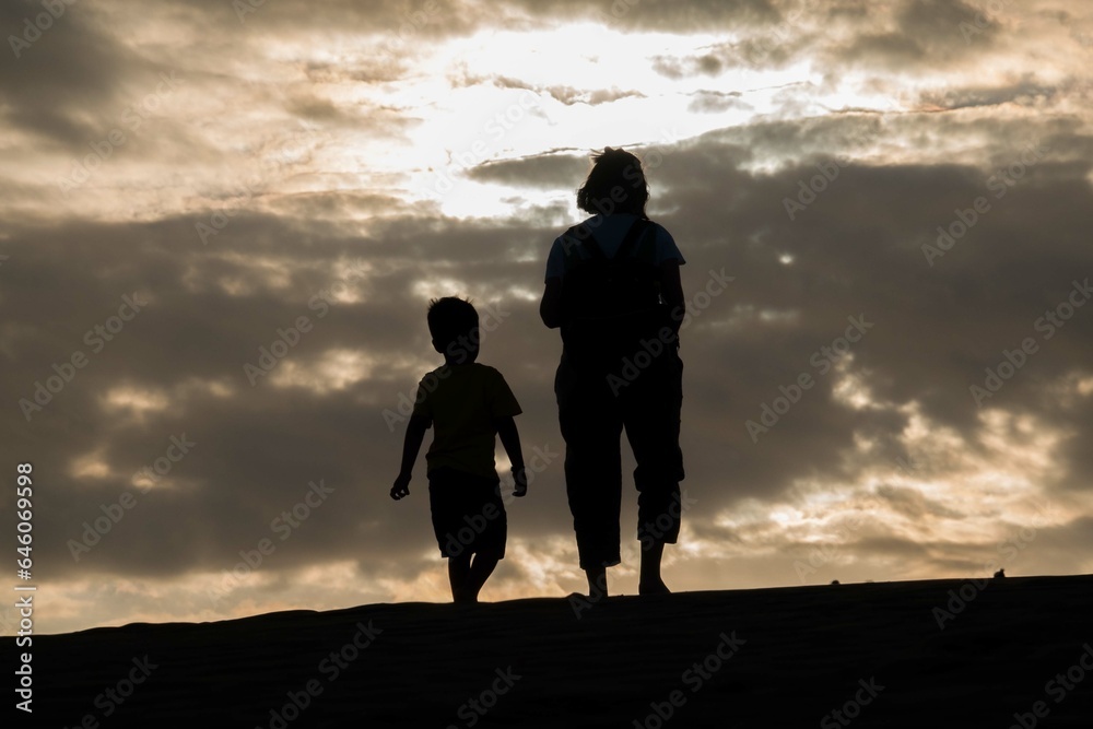 silhouette of couple walking on the beach at sunset