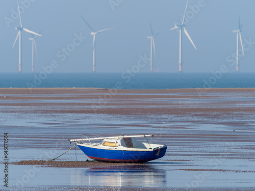Slika na platnu sailboat at low tide with electricity producing wind turbines in the distance