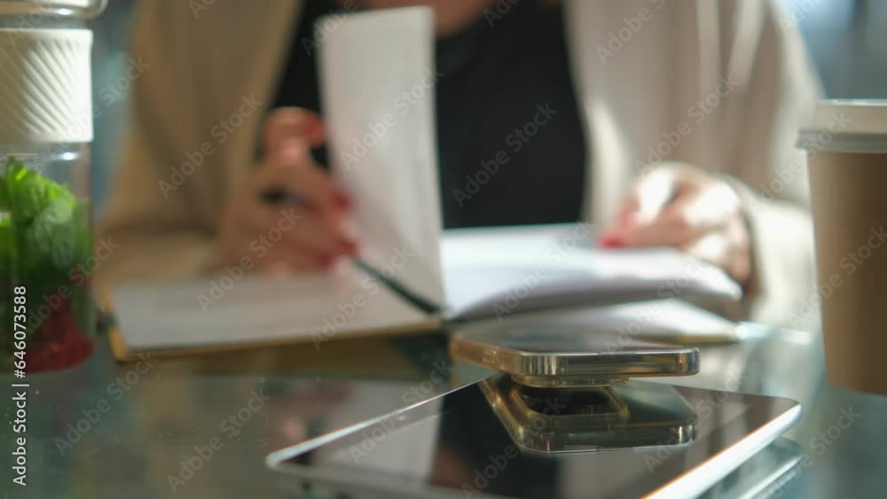 Young business woman sitting at table and writing in notebook. On table is smartphone, and tablet. Freelancer working, writing down new ideas 4K Young business woman sitting at table and writing in notebook. On table is smartphone, and tablet. Freelancer working, writing down new ideas 4K