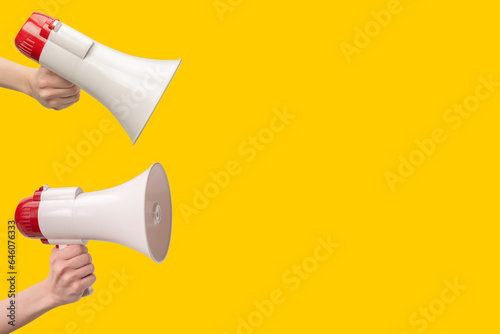 Megaphone in woman hands on a yellow background.