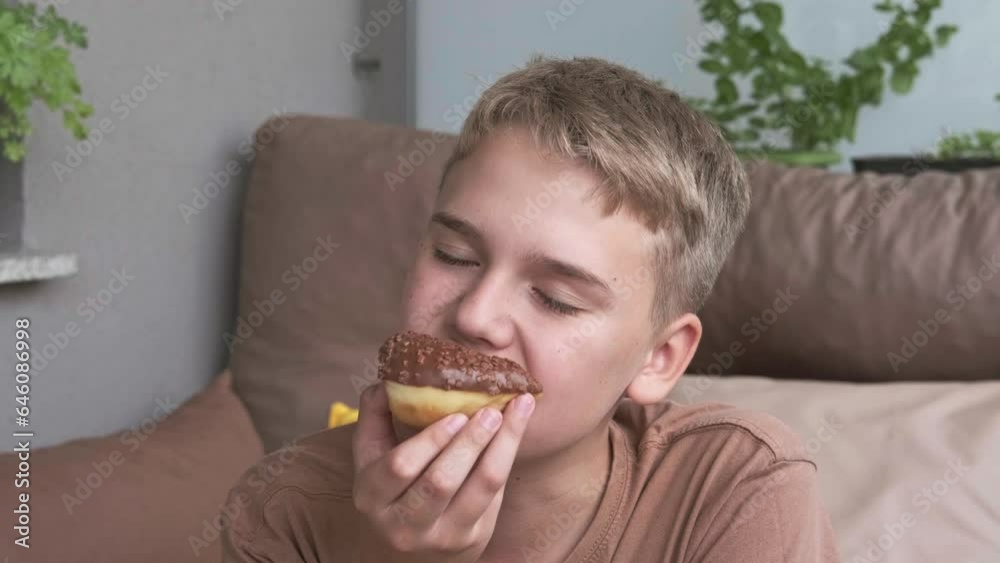A cute guy eats a donut, enjoying the sweet taste of chocolate glaze. A cute guy eats a donut, enjoying the sweet taste of chocolate glaze.