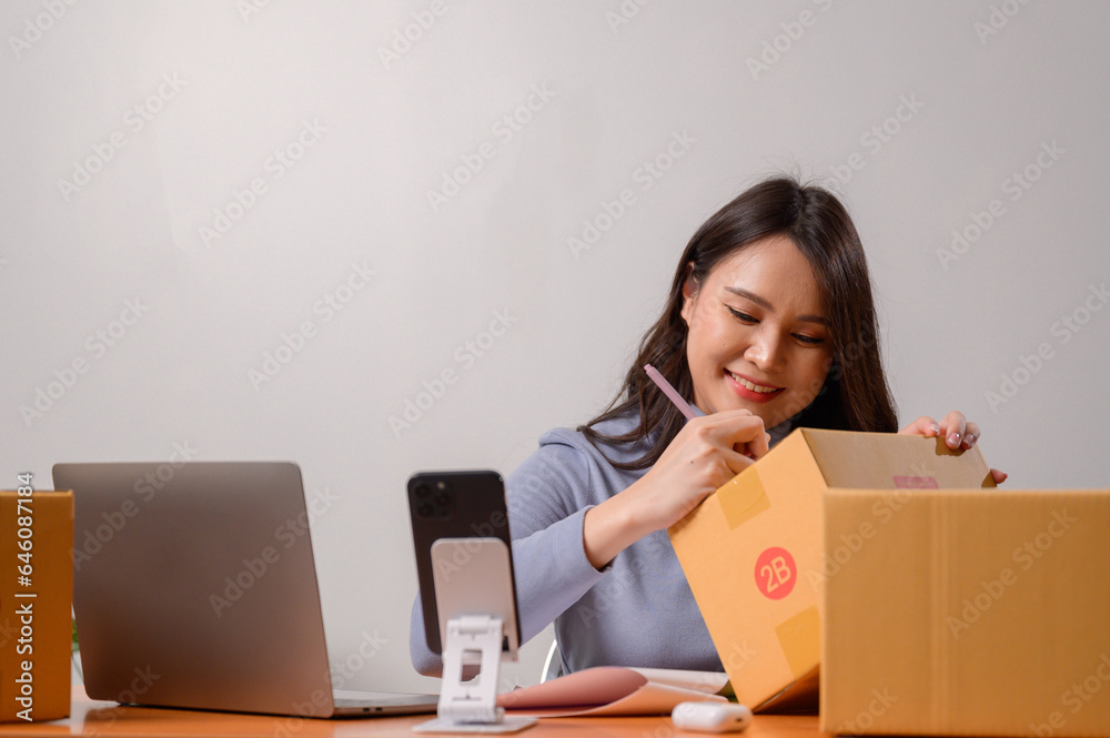 Asian woman selling online using her laptop and working at home You are a small business owner or small business entrepreneur who delivers online marketing packaging boxes. Asian woman selling online using her laptop and working at home You are a small business owner or small business entrepreneur who delivers online marketing packaging boxes.