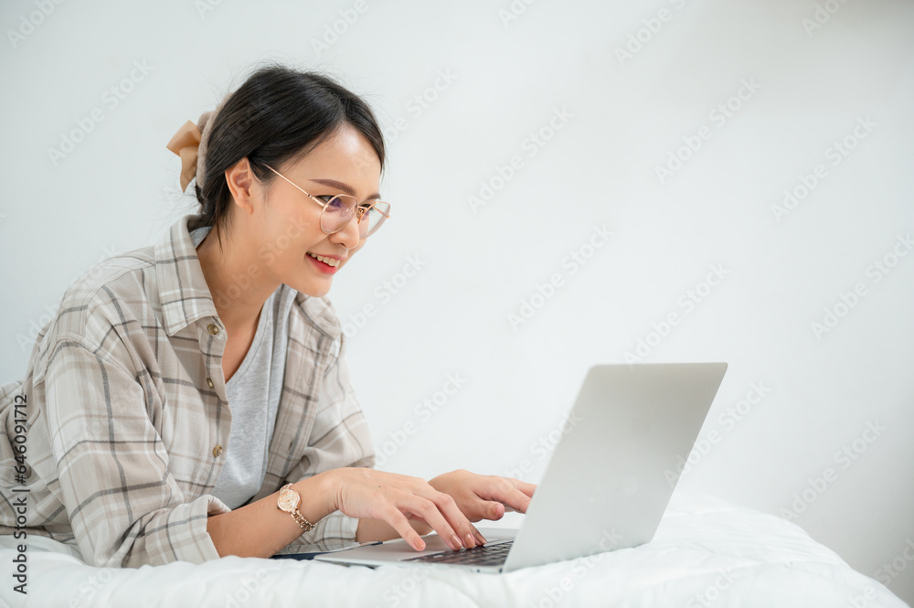 Portrait of Happy Asian freelancer talking remotely online on laptop at her bed at home. Portrait of Happy Asian freelancer talking remotely online on laptop at her bed at home.